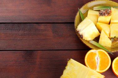 Ananas ve portakal ahşap panoları, ananas ve portakal ahşap zemin, kahvaltı için tropikal meyve salatası yarısı sarı bir plaka üzerinde parçalar