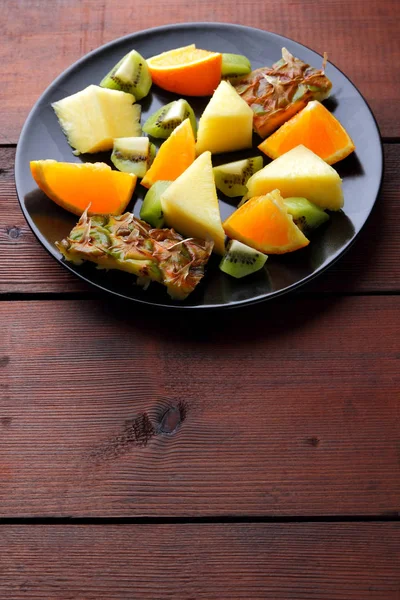 Fruit Salad Vegans Pieces Pineapple Oranges Kiwi Black Plate Tropical — Stock Photo, Image