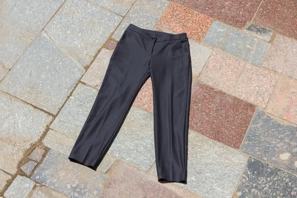 Black men\'s trousers lie on the old porch, dark pants made of natural cloth on a gray background, men\'s clothing on a natural background, tailoring clothes for a store