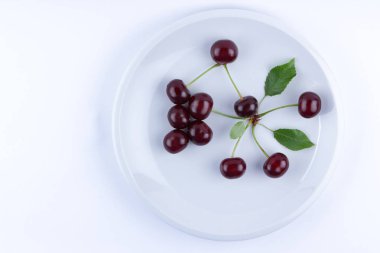 Beyaz tabakta, Minimalizm, vejetaryen yemek, tasarımcı, boş tarzı yeşil yaprakları, kırmızı çilek ile taze kiraz kırmızı kiraz izole