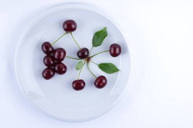 Beyaz tabakta, yeşil yaprakları ile taze kiraz kırmızı kiraz kırmızı minimalizm, vejetaryen yemek, boş tarzında için tasarımcı çilek