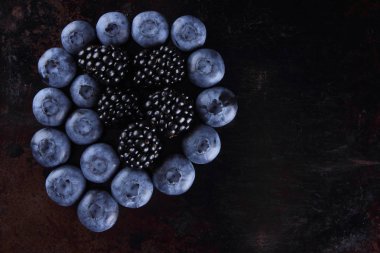 Yaban mersini ve böğürtlen karanlık bir arka plan üzerinde bir vegan meyve bir paslı arka plan, çeşitli berry Kahvaltı, kopya alanı taze çilek