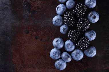 Yaban mersini ve böğürtlen karanlık bir arka plan üzerinde bir vegan meyve bir paslı arka plan, çeşitli berry Kahvaltı, kopya alanı taze çilek