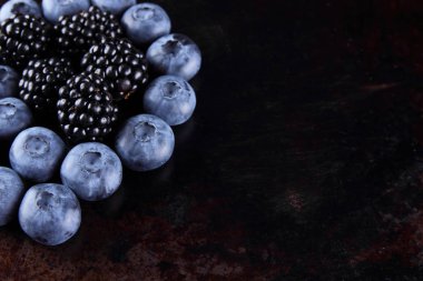 Yaban mersini ve böğürtlen koyu arka plan üzerinde vegan, paslı arka plan üzerinde meyve için taze çilek berry kahvaltı muhtelif