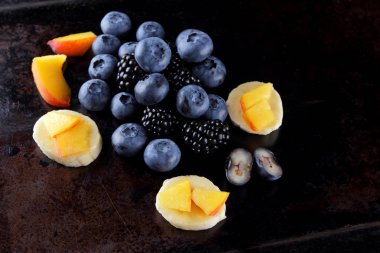 Farklı meyve ve çilek koyu arka plan, taze çilek ve muz ve şeftali vegan, yaban mersini ve kahvaltı için böğürtlen için parçalar