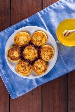 Süzme peynir mavi peçeteye krep. Geleneksel Ukrayna çanak - reçel ahşap zemin ile syrniki. Krep beyaz tabakta bal süzme peynir ile. Kopya alanı