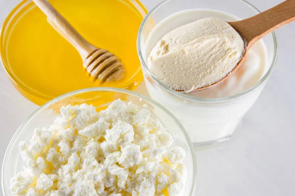 Dairy products and honey with wooden cutlery. Cottage cheese, sour cream, cream on a white background top view. Different natural products for vegan. Healthy food. Copy space
