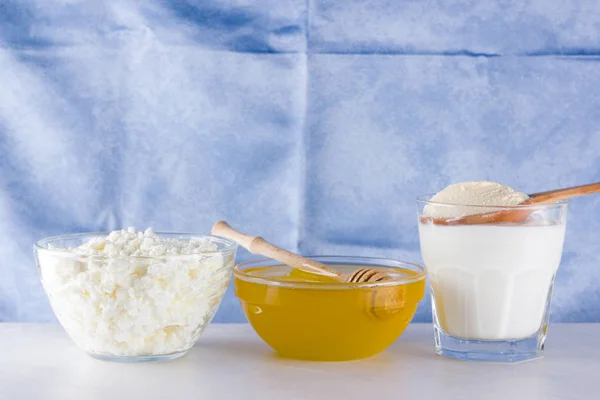 Dairy products and honey with wooden cutlery. Cottage cheese, sour cream, cream on a blue napkin top view. Different natural products for vegan. Healthy food. Copy space