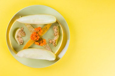 Dilimler ve sarı bir arka plan üzerinde bir kavun içi. Yeşil bir tabakta kavun cilt. Üvez meyveleri renkli bir arka plan üzerinde. Vejetaryen yiyecekler. Yaşam sağlıklı şekilde. Pop Art