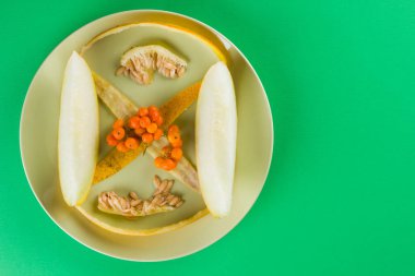 Dilimler ve yeşil bir arka plan üzerinde bir kavun içi. Yeşil bir tabakta kavun cilt. Üvez meyveleri renkli bir arka plan üzerinde. Vejetaryen yiyecekler. Yaşam sağlıklı şekilde. Pop Art