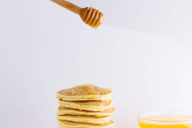 Krep pembe beyaz bir arka plan üzerinde. Kopya alanı ile beyaz tabakta bal ile sıcak krep. Pop sanat tarzı kahvaltı için lezzetli yemek. Tatlım bir tabak üzerinde tahta bir sopa aşağı akar