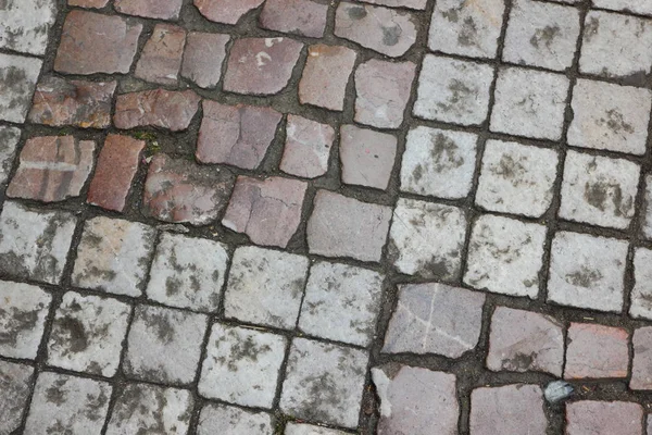 Cobbles close-up. An ancient road lined with a stone in Prague. Texture of smooth stones. Background old stone road in the city. Vintage pattern with natural material