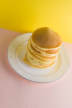 Krep pembe sarı bir arka plan üzerinde. Birçok krep kopya alanı ile beyaz tabakta. Pop sanat tarzı kahvaltı için lezzetli yemek. Festival gıda renkli arka plan üzerinde. Fransız kahvaltı