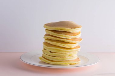 Krep pembe beyaz bir arka plan üzerinde. Kopya alanı ile beyaz tabakta bal ile sıcak krep. Kahvaltı için lezzetli yemek. Tatlım bir tabak üzerinde tahta bir sopa aşağı akar