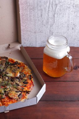 Bira ve pizza. Bir karton kutu İtalyan pizza. Ahşap arka plan üzerinde filtre uygulanmamış Light bira. En sevdiğim yemek erkekler için ayarla