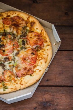 Pizza rustik tarzı ahşap kurullarında. Bir karton kutu İtalyan pizza. Ahşap arka plan basit yemek. Öğle yemeği için lezzetli yemek