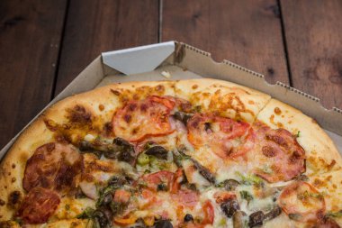 Pizza rustik tarzı ahşap kurullarında. Bir karton kutu İtalyan pizza. Ahşap arka plan basit yemek. Öğle yemeği için lezzetli yemek