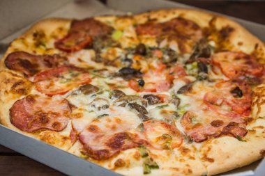 Pizza rustik tarzı ahşap kurullarında. Bir karton kutu İtalyan pizza. Ahşap arka plan basit yemek. Öğle yemeği için lezzetli yemek