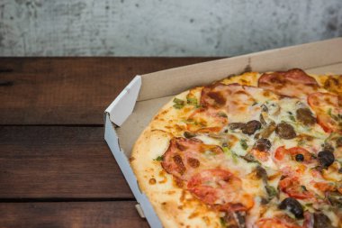 Pizza rustik tarzı ahşap kurullarında. Bir karton kutu İtalyan pizza. Ahşap arka plan basit yemek. Öğle yemeği için lezzetli yemek