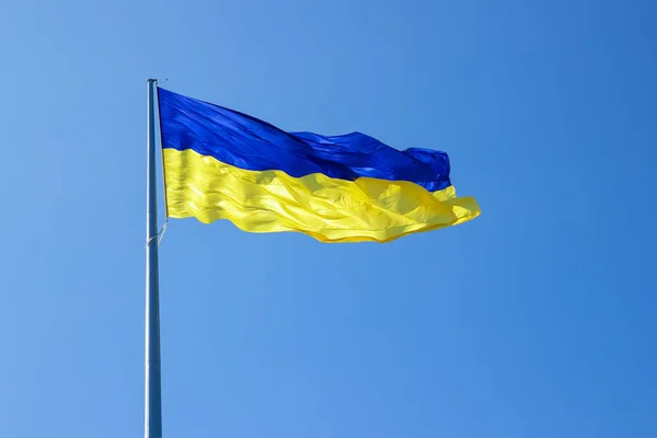 Ukrainian flag. Yellow blue Ukrainian flag on the background of the sky. Ukraine\'s Independence Day. National symbol in the rays of the sun