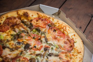 Bir karton kutu İtalyan pizza. Pizza rustik tarzı ahşap arka plan üzerinde. Ahşap arka plan basit yemek. Öğle yemeği için lezzetli yemek