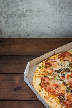 Bir karton kutu İtalyan pizza. Pizza rustik tarzı ahşap arka plan üzerinde. Ahşap arka plan basit yemek. Öğle yemeği için lezzetli yemek