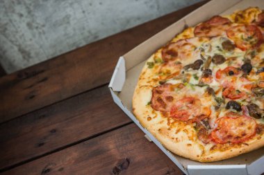Bir karton kutu İtalyan pizza. Pizza rustik tarzı ahşap arka plan üzerinde. Ahşap arka plan basit yemek. Öğle yemeği için lezzetli yemek