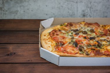 Pizza rustik tarzı ahşap arka plan üzerinde. İtalyan pizza dükkanı işleten bir karton kutu içinde. Ahşap arka plan basit yemek. Öğle yemeği için lezzetli yemek