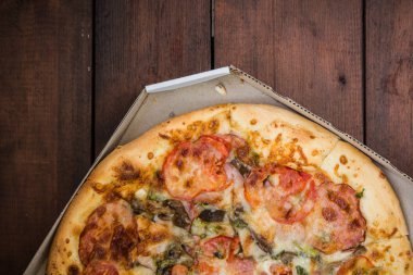 Pizza rustik tarzı ahşap arka plan üzerinde. İtalyan pizza dükkanı işleten bir karton kutu içinde. Ahşap arka plan basit yemek. Öğle yemeği için lezzetli yemek