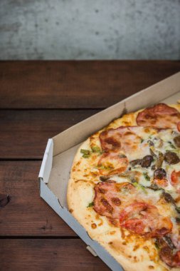 Pizza rustik tarzı ahşap arka plan üzerinde. İtalyan pizza dükkanı işleten bir karton kutu içinde. Ahşap arka plan basit yemek. Öğle yemeği için lezzetli yemek