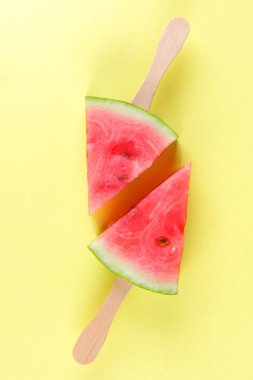Karpuz pop art. Karpuz bir çubuk üzerinde sarı bir arka plan üzerinde parçaları. Minimalist tarzda doğal bir tatlı. Bir vegan gıda ile yaratıcı hikaye