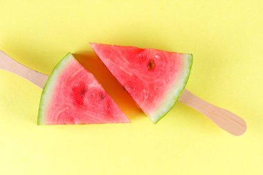 Karpuz pop art. Karpuz bir çubuk üzerinde sarı bir arka plan üzerinde parçaları. Minimalist tarzda doğal bir tatlı. Bir vegan gıda ile yaratıcı hikaye