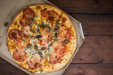 Pizza rustik tarzı ahşap arka plan üzerinde. İtalyan pizza dükkanı işleten bir karton kutu içinde. Ahşap arka plan üzerinde basit gıda