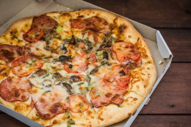 Pizza rustik tarzı ahşap arka plan üzerinde. İtalyan pizza dükkanı işleten bir karton kutu içinde. Ahşap arka plan üzerinde basit gıda