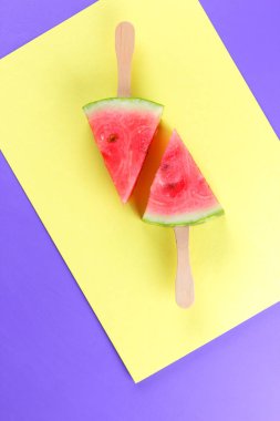 Karpuz pop art. Karpuz Stick sarı mor arka plan üzerinde parçaları. Doğal tatlı minimalist tarzda. Vegan gıda ile yaratıcı hikaye