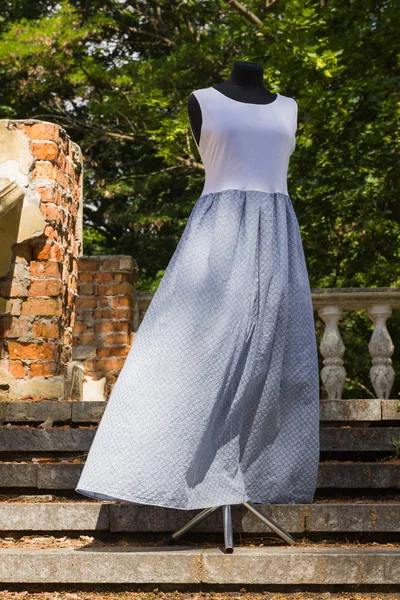 Summer long dress of jersey. White blue dress on mannequin. Female sarafan made of natural fabric. Natural background. Copy space