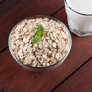 Yulaf ezmesi, süt ve nane. Ahşap kurullarında yulaf gevreği. Süt ve yulaf ezmesi kahvaltı için. Sağlıklı gıda. Vejetaryen yiyecekler. Minimalizm