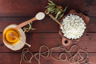 Süzme peynir ve krem. Yumuşak peynir ve bal ahşap kurullarında. Çanak çömlek ve ıhlamur çiçek süzme peynir. Ahşap arka plan üzerinde sicim. Tahta kaşık krem. Ahşap stand tatlım. Kopya alanı