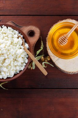 Süzme peynir ve krem. Yumuşak peynir ve bal ahşap kurullarında. Çanak çömlek ve ıhlamur çiçek süzme peynir. Ahşap arka plan üzerinde sicim. Tahta kaşık krem. Ahşap stand tatlım. Kopya alanı