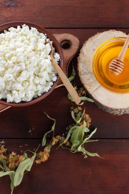 Süzme peynir ve krem. Yumuşak peynir ve bal ahşap kurullarında. Çanak çömlek ve ıhlamur çiçek süzme peynir. Ahşap arka plan üzerinde sicim. Tahta kaşık krem. Ahşap stand tatlım. Kopya alanı