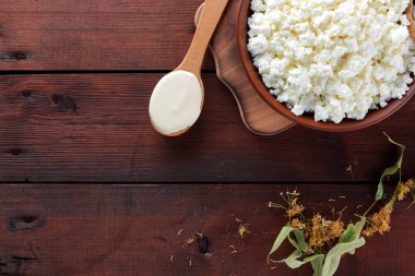 Süzme peynir ve krem. Süt ürünleri ahşap kurullarında. Çanak çömlek ve ıhlamur çiçek süzme peynir. Tahta kaşık krem. Kopya alanı