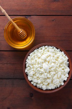 Süzme peynir ve bal. Yumuşak peynir ve bal ahşap kurullarında. Çanak çömlek tabak içinde süzme peynir. Ahşap stand tatlım. Kopya alanı
