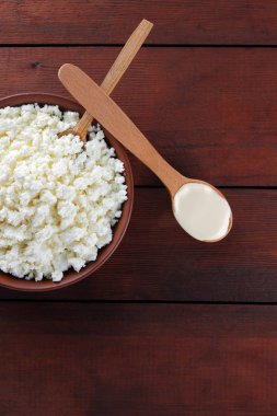 Süzme peynir. Süzme peynir ve krem ahşap kurullarında. Toprak çanak yumuşak beyaz peynir. Süt ürünleri tahta kaşıkla. Kaşığı ekşi krema. Kopya alanı