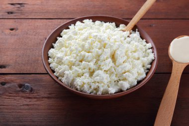 Süzme peynir. Süzme peynir ve krem ahşap kurullarında. Toprak çanak yumuşak beyaz peynir. Süt ürünleri tahta kaşıkla. Kaşığı ekşi krema. Kopya alanı