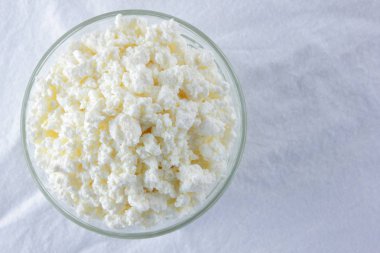 Süzme peynir. Beyaz arka plan üzerinde süzme peynir. Cam beyaz peçete üzerinde suda peynir. Kahvaltıda süt ürünleri. Kopya alanı