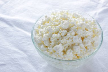 Süzme peynir. Beyaz arka plan üzerinde süzme peynir. Cam beyaz peçete üzerinde suda peynir. Kahvaltıda süt ürünleri. Kopya alanı