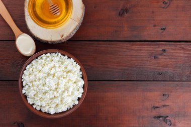 Süzme peynir ve krem. Yumuşak peynir ve bal ahşap kurullarında. Çanak çömlek içinde süzme peynir. Tahta kaşık krem. Ahşap stand tatlım. Kopya alanı