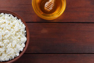 Süzme peynir ve bal. Yumuşak peynir ve bal ahşap kurullarında. Çanak çömlek tabak içinde süzme peynir. Ahşap stand tatlım. Kopya alanı