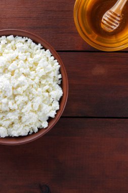 Süzme peynir ve bal. Yumuşak peynir ve bal ahşap kurullarında. Çanak çömlek tabak içinde süzme peynir. Ahşap stand tatlım. Kopya alanı