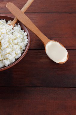 Süzme peynir. Süzme peynir ve krem ahşap kurullarında. Toprak çanak yumuşak beyaz peynir. Süt ürünleri tahta kaşıkla. Kaşığı ekşi krema. Kopya alanı